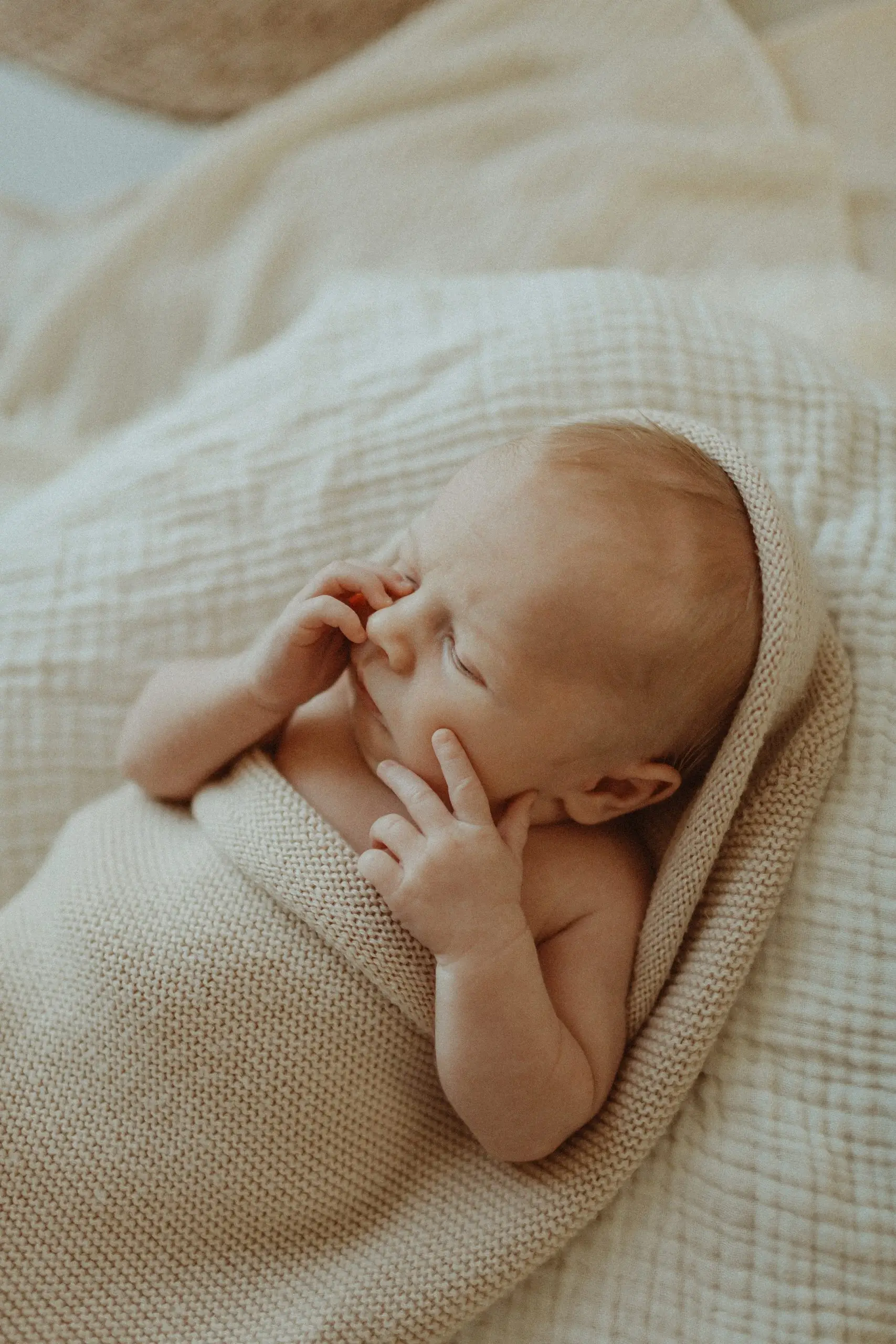 Slapende pasgeboren baby in een zacht gebreid dekentje