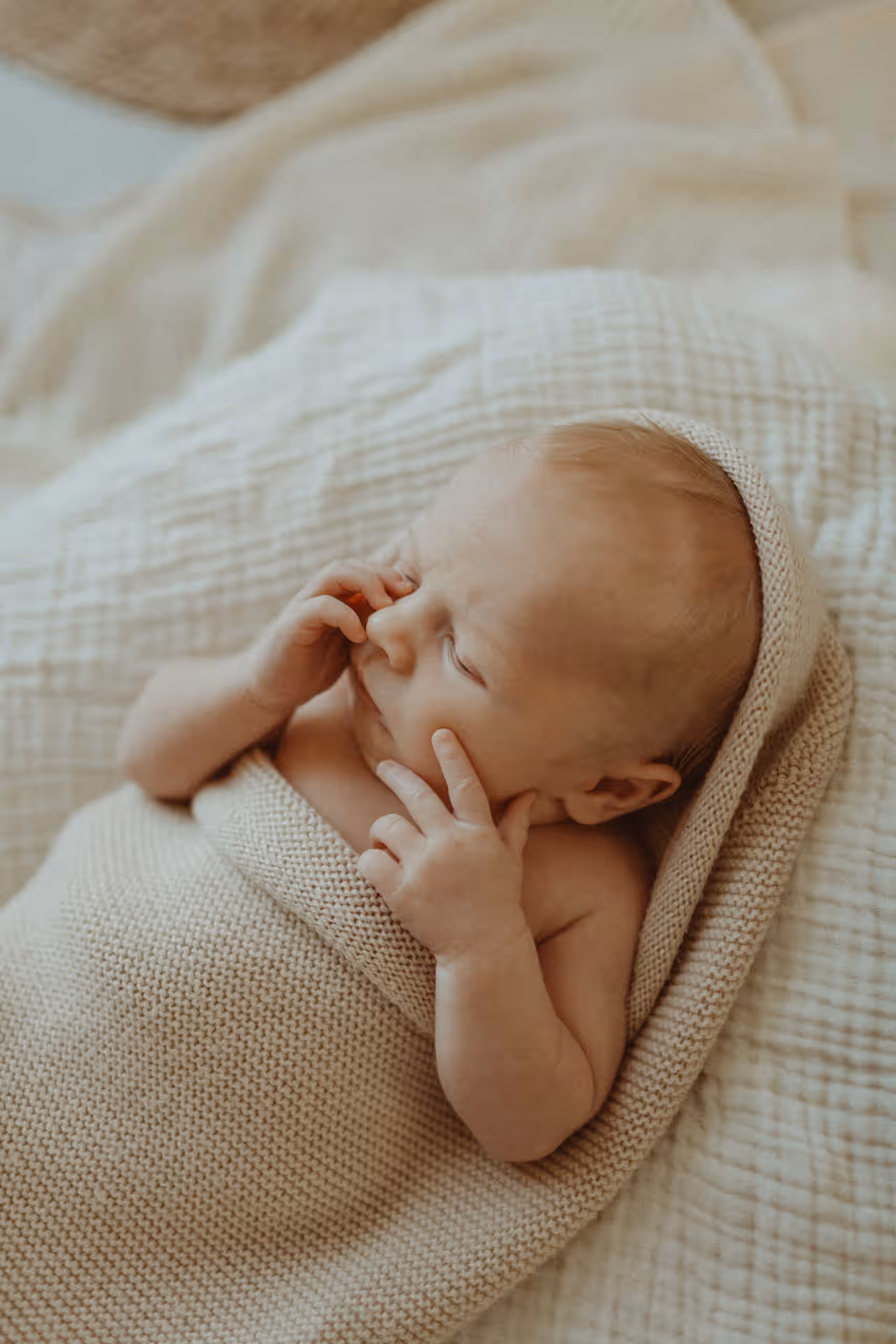 Slapende pasgeboren baby in een zacht gebreid dekentje