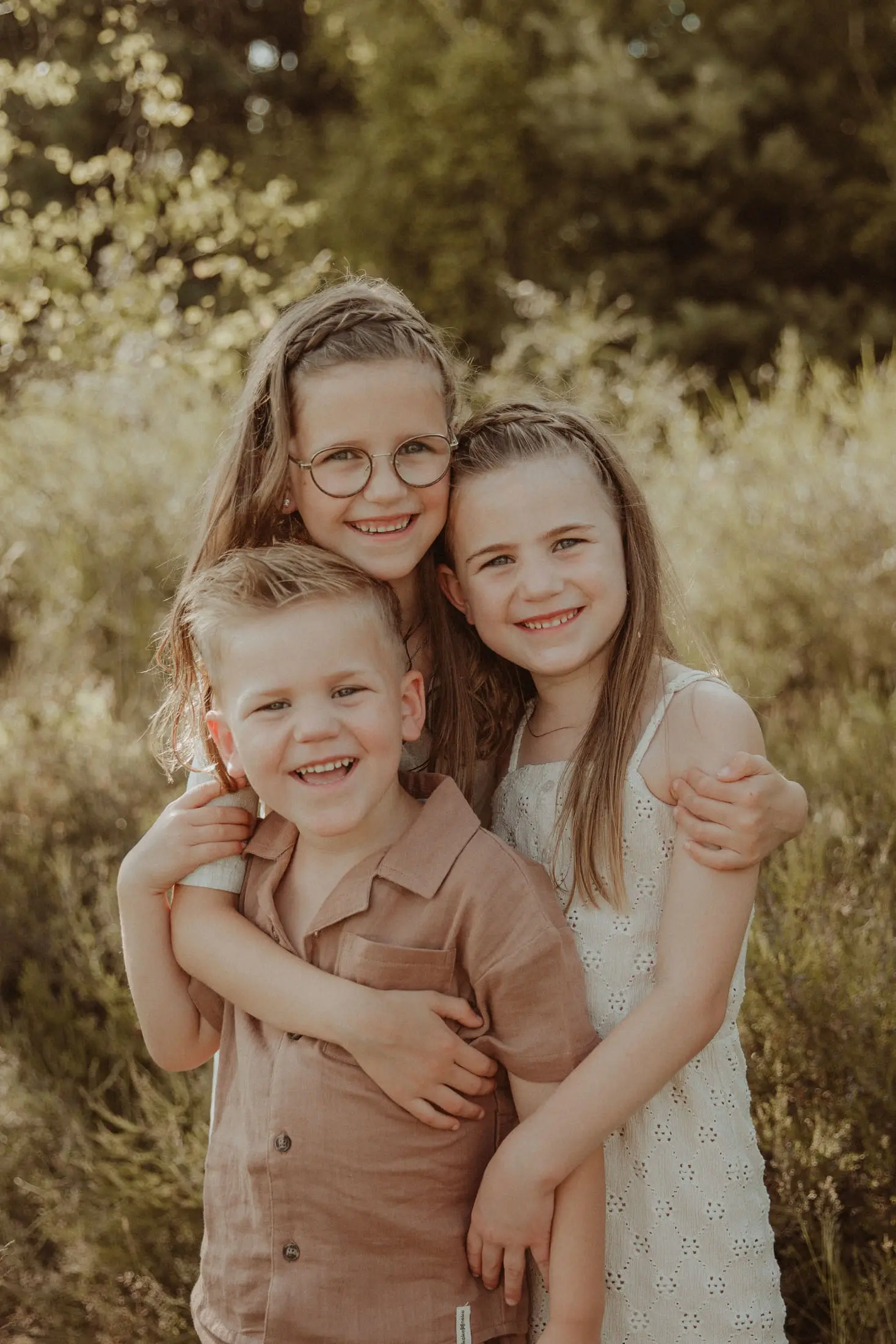 Drie kinderen lachen samen tijdens een buitenshoot