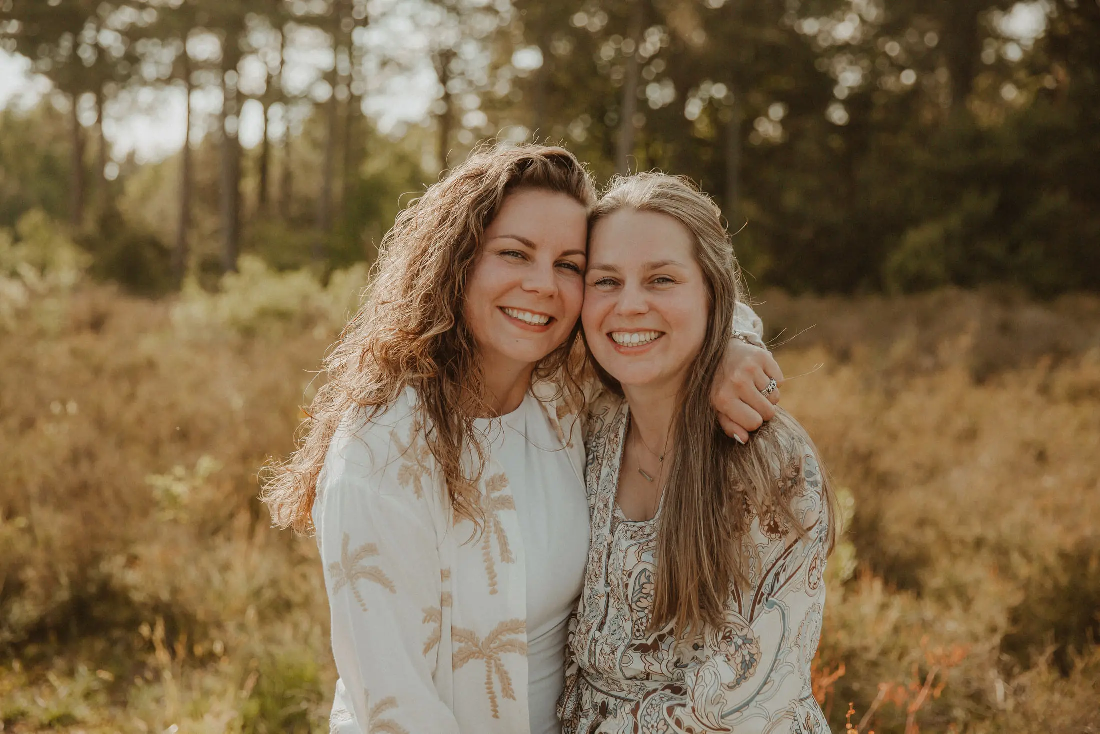 Twee vrouwen lachen samen in warm buitenlicht