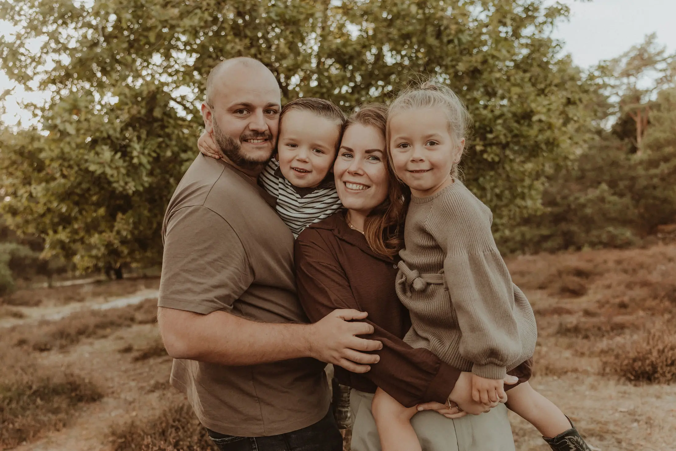 Ouders knuffelen hun kinderen tijdens een familieshoot