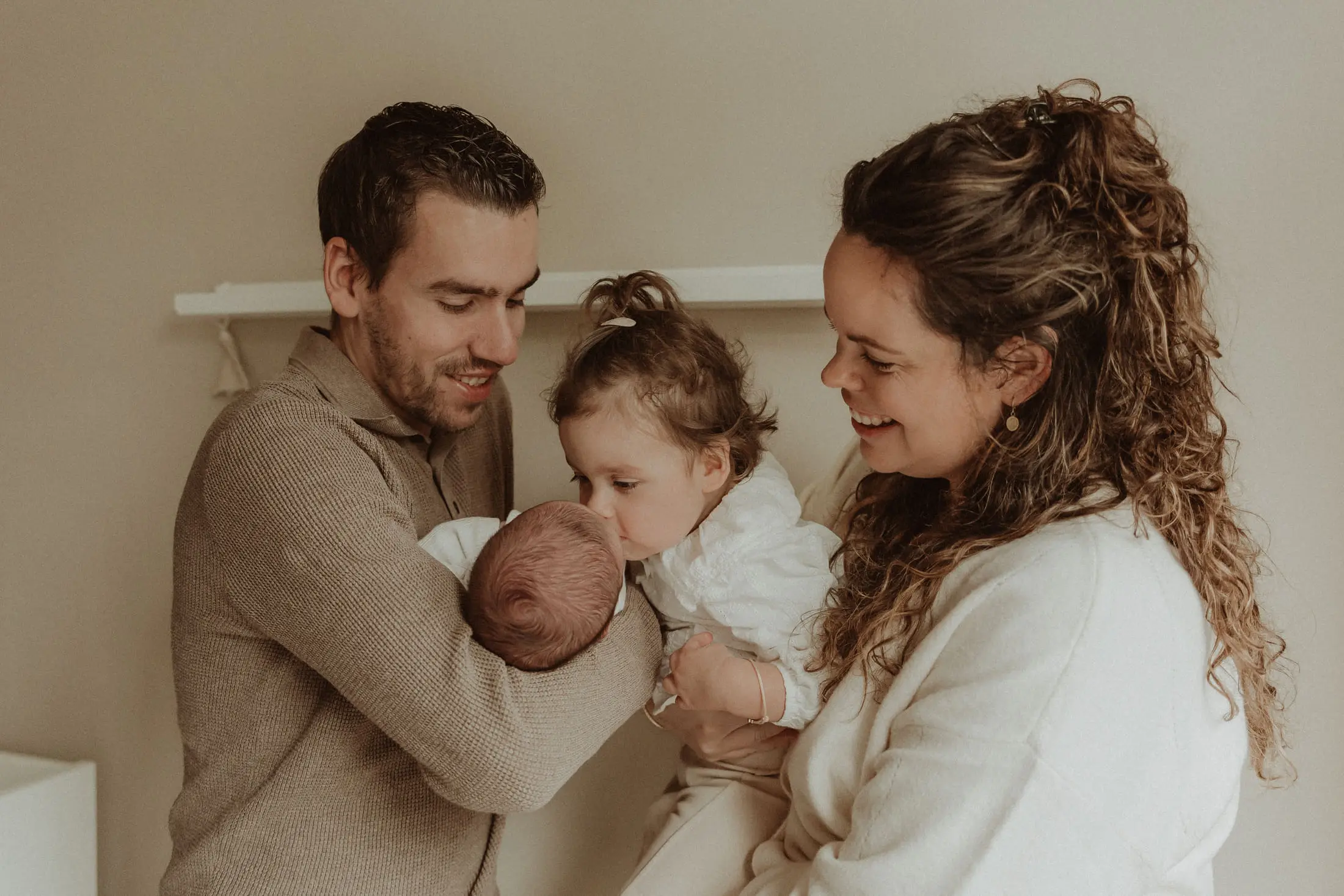 Ouders en grote zus kijken liefdevol naar hun pasgeboren baby