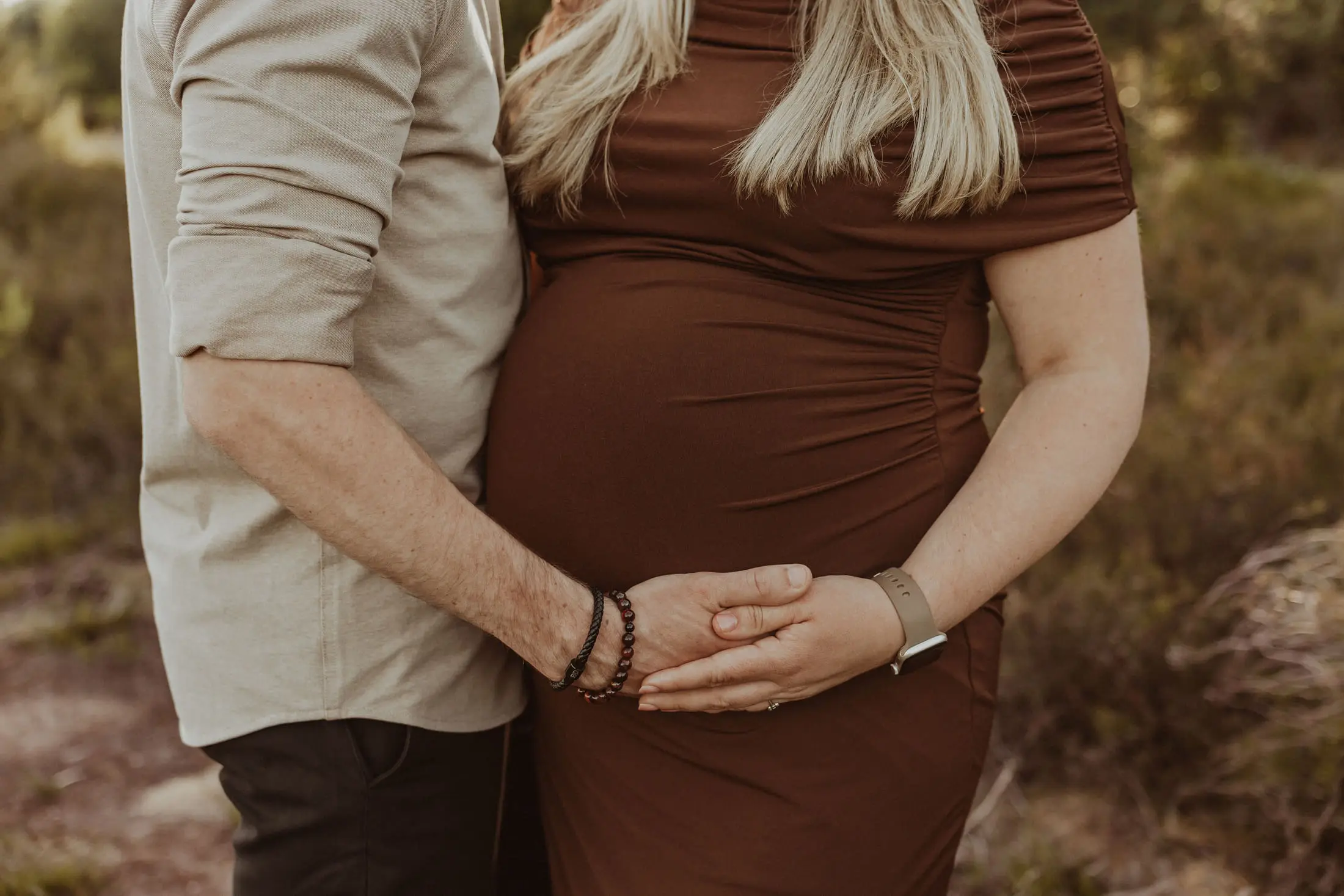 Zwangere vrouw en haar partner houden samen de buik vast