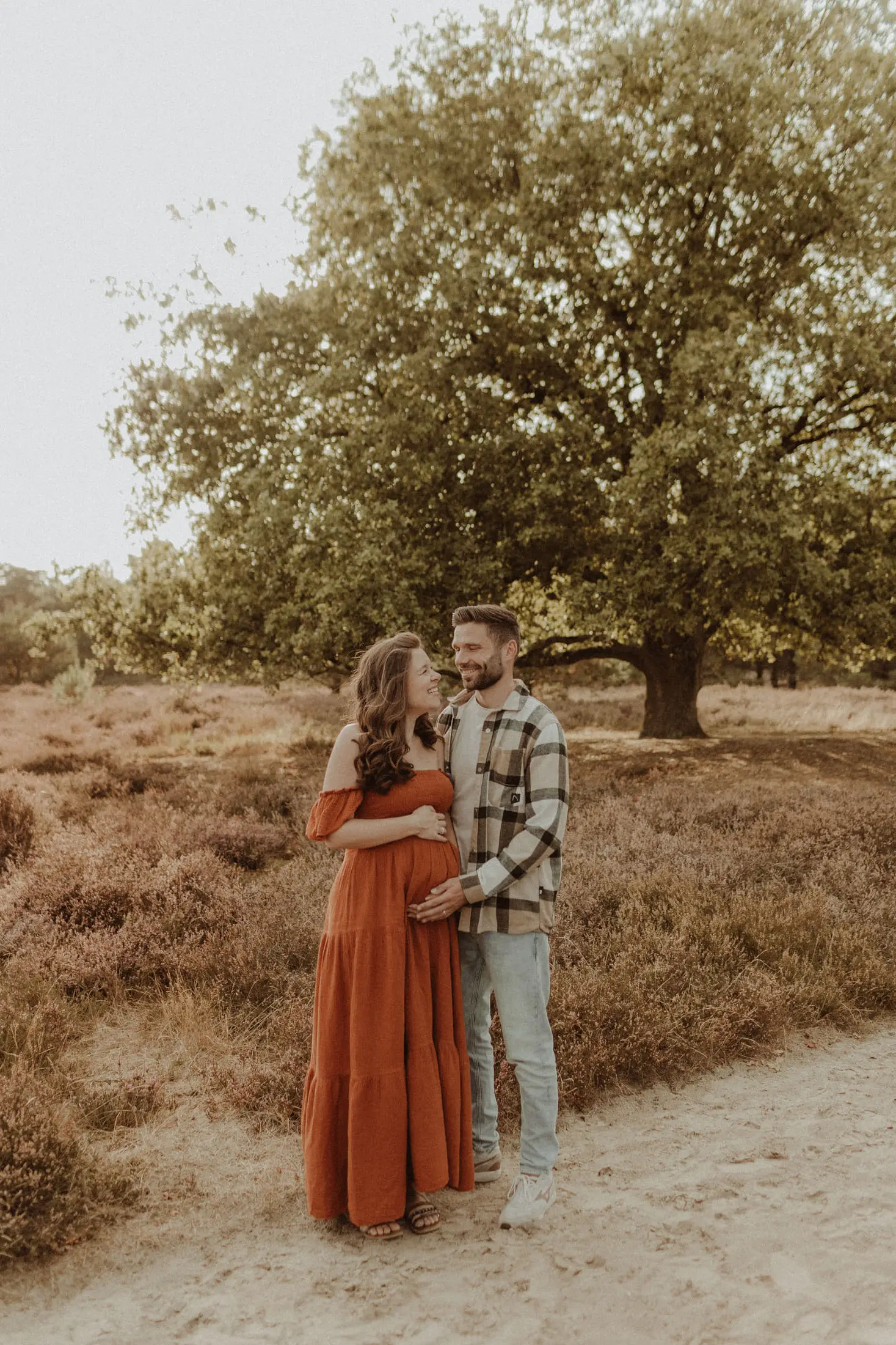 Zwanger stel staat samen in een open natuurgebied